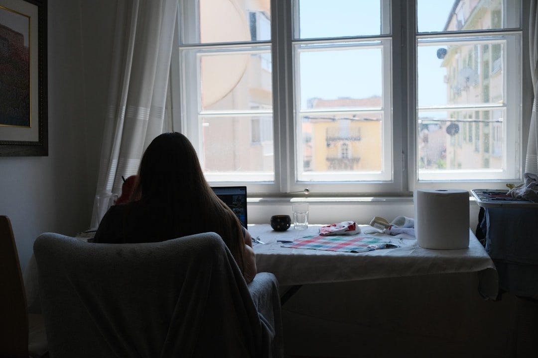 Person works near a bright window in a room.
