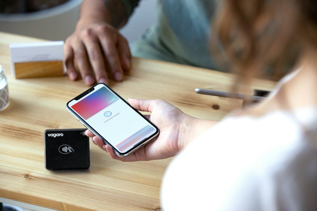 Woman holds smartphone near card reader for transaction