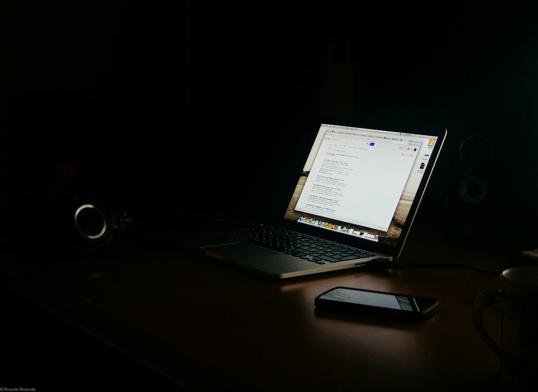 A laptop and phone on a dimly lit work desk