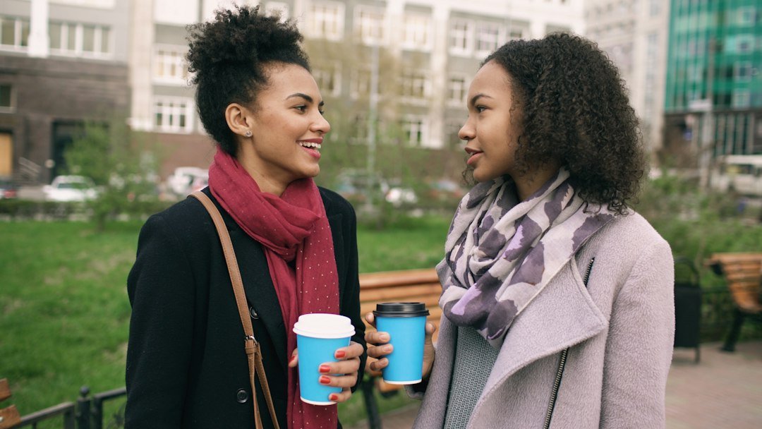 Two women talking while holding coffee cups