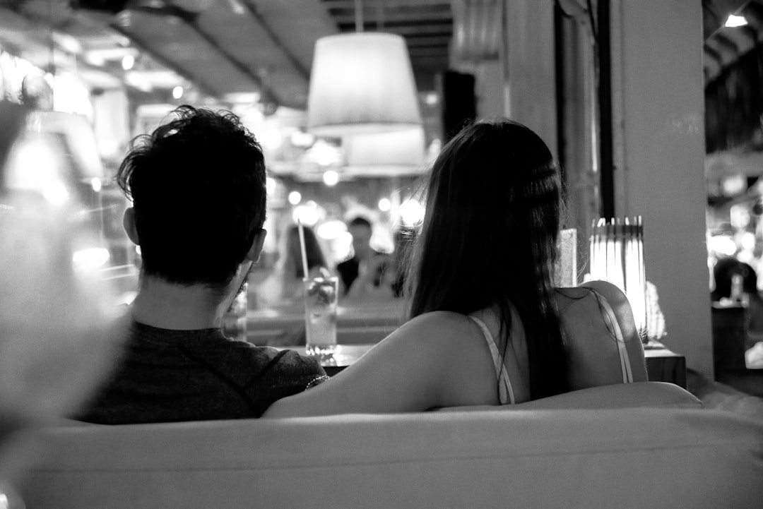 grayscale photo of couple sitting on chair